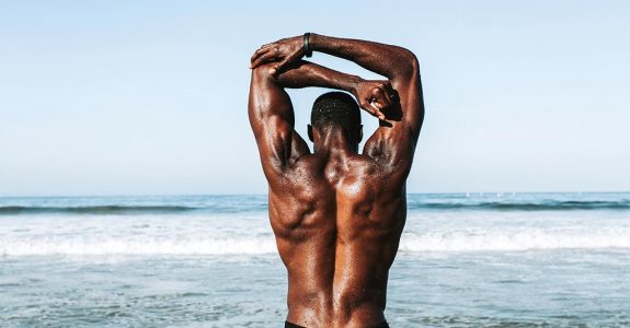 A man's back standing on a beach