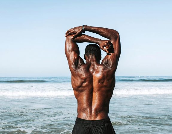 A man's back standing on a beach