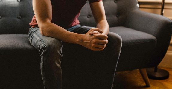 A man sitting on a couch in a psychotherapist's office.