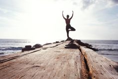 A woman standing in a yoga pose on a pier
